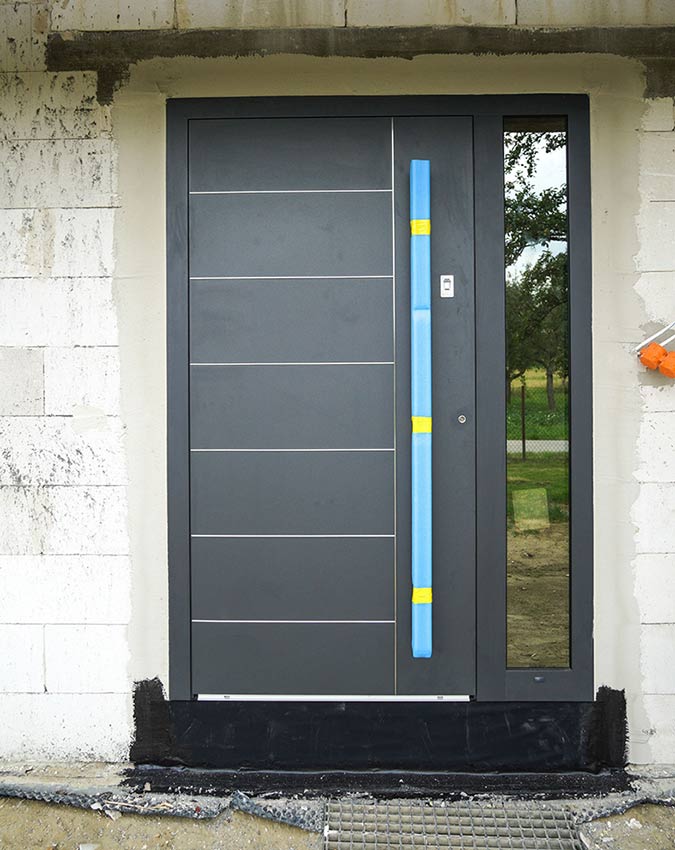 Drzwi aluminiowe Aluhaus. Wyposażenie: czytnik linii papilarnych, kryte zawiasy, pochwyt, szklenie refleks. Kolor: antracyt quartz Szczelny montaż + podwalina pod drzwi + zabezpieczenie. Źródło: Ferdo